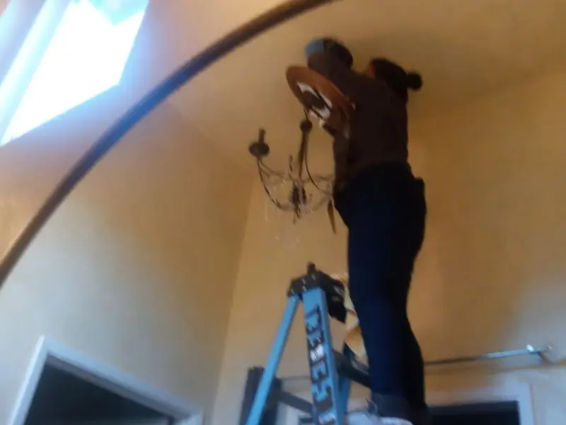 Electrician installing a chandelier in a McGregor residence